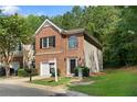 Well-maintained townhome exterior features a brick facade, attached garage, and lush green lawn at 4221 Rogers Creek Ct, Duluth, GA 30096