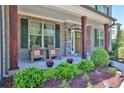Inviting front porch with stone accents, wooden pillars, and a seating area at 13015 Fox Rd, Alpharetta, GA 30005