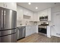 Modern kitchen features stainless steel appliances, white cabinets, and plank flooring at 5 Palace Green Place Nw, Atlanta, GA 30318