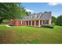 Attractive home with brick facade, black shutters, covered entry, and meticulously maintained lawn at 65 Pecan Ln, Oxford, GA 30054