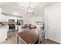 Open kitchen with stainless steel appliances, white cabinets, breakfast bar, and adjacent dining area with hardwood floors at 2850 Winchester Dr, Cumming, GA 30041