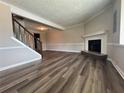Living room view featuring wood floors, a cozy fireplace, and staircase access to the upper level at 8170 Canyon Forge Dr, Riverdale, GA 30274