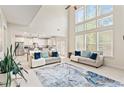 Bright living room boasts high ceilings, large windows, modern furnishings, and seamless transition to the kitchen at 297 Aylesbury Blvd, Mcdonough, GA 30252