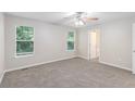 Bright bedroom features neutral carpet, a ceiling fan, and natural light from large windows at 7420 Bristol Cir, Douglasville, GA 30134