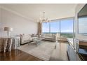 Bright living room features floor-to-ceiling windows with city views, modern chandelier, and hardwood flooring at 3630 Peachtree Ne Rd # 2706, Atlanta, GA 30326
