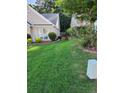 Lush side yard with a brick border, a vibrant green lawn, and mature shrubs and plants at 979 Simonton Glen Dr, Lawrenceville, GA 30045