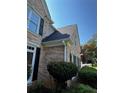 Close-up of a brick house featuring well-maintained gutters, black shutters, and lush greenery at 2550 Lynshire Ln, Snellville, GA 30078