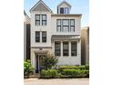 Charming, modern, three-story white brick home with black-trimmed windows, black metal fence, and verdant landscaping at 506 Broadview Ne Pl, Atlanta, GA 30324