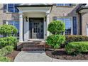 Close-up of a front door with beautiful shrubbery, plants and flowers around the entry at 1723 Woodbow Path, Dacula, GA 30019