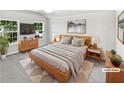 Staged main bedroom with large windows, neutral walls, and modern wood furniture at 2438 Suwanee Pointe Dr, Lawrenceville, GA 30043