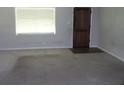 Empty living room with neutral carpet, large window, and a view of a solid wood door at 2842 Jordan Forest Trail Northwest, Lawrenceville, GA 30044
