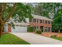 Two-story brick home with a two-car garage, lush landscaping, and inviting curb appeal at 3375 Rivendell Ct, Roswell, GA 30075