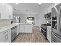 Modern kitchen boasts white cabinets, stainless steel appliances, and a view to the backyard at 1644 Royal Ives Dr, Lawrenceville, GA 30045