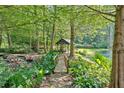 Lush backyard featuring a serene pond, bridge, and gazebo surrounded by lush greenery at 3122 Harmony Rd, Temple, GA 30179