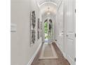Elegant hallway featuring hardwood floors, barrel ceiling, decorative sconces, and an arched front door at 117 Via Roma, Woodstock, GA 30188