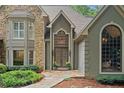 Elegant stone and stucco exterior with arched windows and a grand front door, surrounded by lush landscaping at 4435 Pemberton Cv, Johns Creek, GA 30022