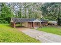 A brick house, featuring a carport and a long driveway, nestled amidst a lush, green landscape at 4748 Carson Sw Pass, Atlanta, GA 30331