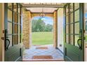 Elegant entryway with stone archway, decorative lighting, and a view of the landscaped front yard at 6685 Driskell Rd, Cumming, GA 30041