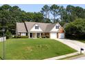 Traditional home exterior with lush green lawn, mature trees, and a welcoming front porch at 964 Natural Brook Trl, Lawrenceville, GA 30045