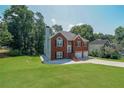 Charming exterior view of a brick home with a lush green lawn, mature trees, and a two-car garage at 503 Rising Dr, Woodstock, GA 30189