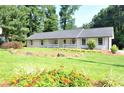 Beautiful single-story home with a lush green lawn and colorful flowerbeds at 5974 Sw Four Winds Sw Dr, Lilburn, GA 30047