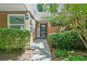 Inviting brick townhome entrance featuring a black door, lush green bushes, and a brick facade at 22 Dunwoody Springs Dr, Atlanta, GA 30328
