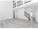 Open-concept living area with high ceilings, gray wood floors, iron-railed loft, and plenty of natural light at 2023 Jameson Cir, Lawrenceville, GA 30043