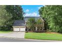 Traditional brick home with a two-car garage, surrounded by mature trees and a lush lawn, offering curb appeal at 2031 Greyfield Nw Dr, Kennesaw, GA 30152