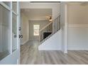 Welcoming foyer with staircase, wood floors, and natural light streaming through the doorway and window at 443 Lothbury Ave, Locust Grove, GA 30248