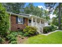 Brick home features a welcoming covered front porch with white railings, framed by well-maintained landscaping at 1959 Audubon Ne Dr, Atlanta, GA 30329