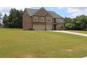 Lush green lawn surrounds a spacious two-story brick home, complete with a three-car garage at 293 Ironwood Dr, Stockbridge, GA 30281