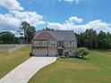 Expansive front lawn leads to a stately brick home with a three-car garage at 293 Ironwood Dr, Stockbridge, GA 30281