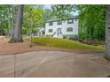 View of home exterior featuring lush lawn and a long driveway, with mature trees in the background at 9805 Buice Rd, Alpharetta, GA 30022