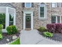 Charming home entry featuring a dark wood door with a wreath, surrounded by lush greenery and elegant stone accents at 2115 Bentbrooke Trl, Lawrenceville, GA 30043
