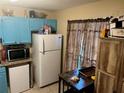 Kitchen with blue cabinets, white refrigerator, and tile floor at 8564 Jamestown Way, Jonesboro, GA 30238