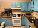 Kitchen features include outdated blue cabinets, tan granite countertops, and a white gas range at 8564 Jamestown Way, Jonesboro, GA 30238
