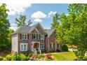 Beautiful brick home featuring manicured landscaping, green lawn, and mature trees at 7048 Bennington Ln, Cumming, GA 30041
