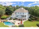 Aerial view of an outdoor living space with a pool, spa, covered patio, outdoor kitchen, and a fire pit with seating at 6325 Haddington Ln, Suwanee, GA 30024