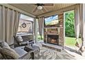 Cozy covered patio with stone fireplace, ceiling fan, and comfortable seating area at 4227 Meadow Wind Dr, Snellville, GA 30039