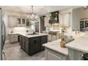 Elegant kitchen featuring a center island with seating, custom cabinets, stone countertops, stainless steel appliances, and modern lighting at 6715 Bentley Trl, Cumming, GA 30040
