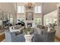 Sophisticated living room with high ceilings, a fireplace, large windows, elegant furnishings, and a grand piano at 6715 Bentley Trl, Cumming, GA 30040