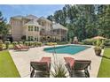 Backyard oasis with a large in-ground pool, lounge chairs, covered porch, stone fireplace, and beautifully landscaped surroundings at 6715 Bentley Trl, Cumming, GA 30040