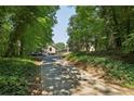 View of the long driveway leading to the home surrounded by mature trees and lush greenery at 1024 Lake Charles Dr, Roswell, GA 30075