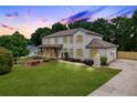 Stately two-story home with painted brick, front porch, long driveway, and professionally landscaped yard at dusk at 2015 Clipper Straits, Snellville, GA 30078
