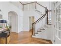 Bright foyer featuring hardwood floors, a staircase with white railings, and an open doorway to a living space at 5355 Highland Pine Ln, Mableton, GA 30126