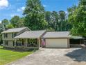 Charming two-story home featuring a metal roof, cozy front porch, and attached two car garage, surrounded by lush trees at 2081 Old Peachtree Road Northeast Rd, Lawrenceville, GA 30043