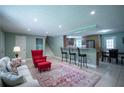 Open-concept living room featuring a bar area and a stylish red armchair with plush, neutral furnishings at 2081 Old Peachtree Road Northeast Rd, Lawrenceville, GA 30043