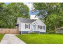 A cozy painted brick home with blue shutters sits on a verdant lawn with a welcoming front porch and ample greenery at 512 Allendale Dr, Decatur, GA 30032