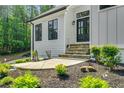 Front door featuring professional landscaping with black mulch, green plants, and stone steps at 6070 Lively Ct, Cumming, GA 30040