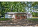 Quaint one-story home with charming front porch and shuttered windows surrounded by mature trees on a spacious lot at 995 Highway 101 S, Temple, GA 30179